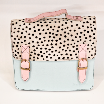 Mala tipo saco azul claro com aba creme e bolinhas pretas, alça e detalhes em rosa