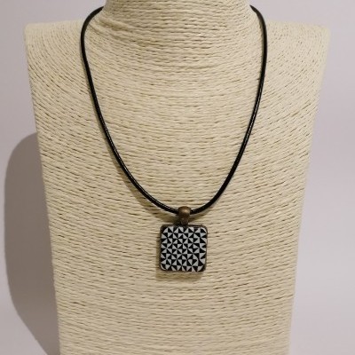 Colar com pendente quadrado preto e branco com padrão geométrico em busto de tecido bege
