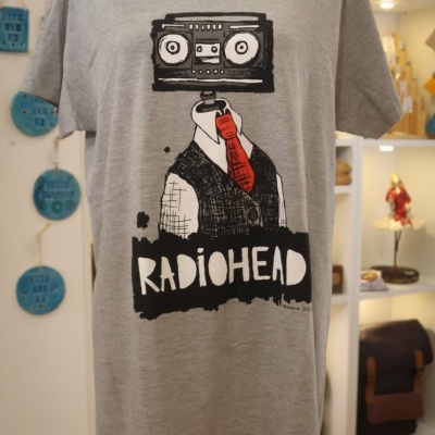 T-shirt cinzenta com estampado de figura com cabeça de rádio e texto RADIOHEAD