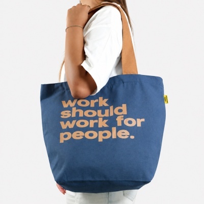 Blue canvas tote bag with brown handles and tan text on it
