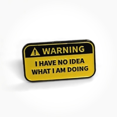 Rectangular yellow and black metal pin with warning text and symbol