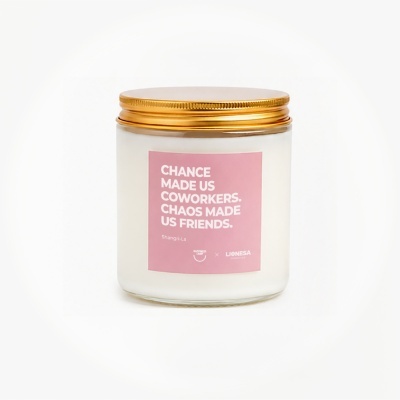 White candle jar with gold lid and pink label with white text