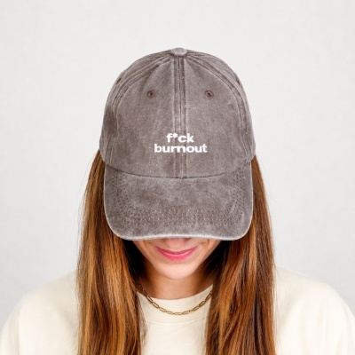 Brown baseball cap with white f*ck burnout text, worn by person with long hair