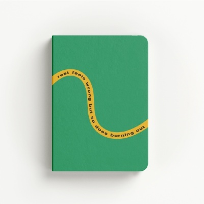 Green notebook with yellow curved stripe and black motivational text on the cover