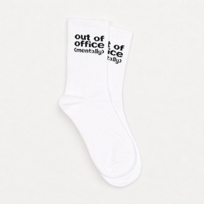 White crew socks with the text out of office (mentally) in black near the top