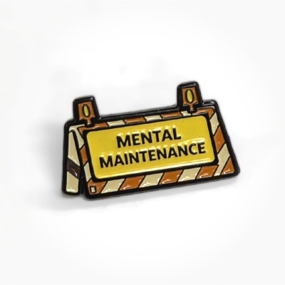 Enamel pin shaped like a construction barrier with the text MENTAL MAINTENANCE