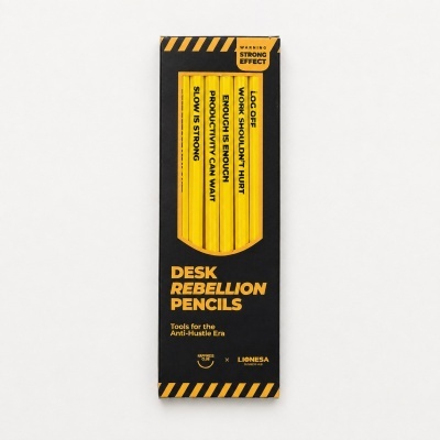 Box of yellow pencils with anti-hustle phrases and black and yellow packaging labeled Desk Rebellion Pencils.