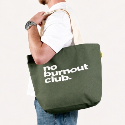 Green tote bag with no burnout club. text carried by person