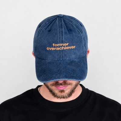 Navy blue baseball cap with orange text worn by person with facial hair