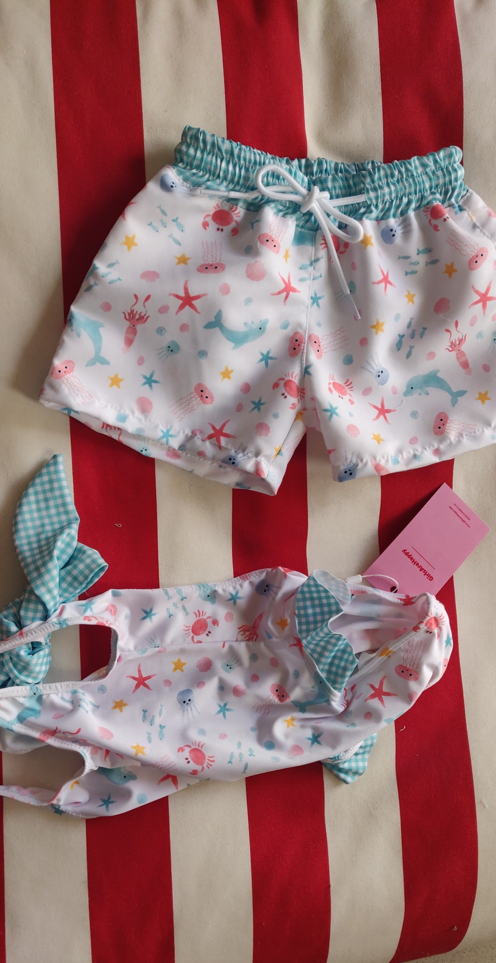 Conjunto de roupa de banho infantil branca com padrão colorido de animais marinhos e detalhes verdes