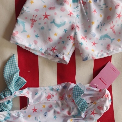 Conjunto de roupa de banho infantil branca com padrão colorido de animais marinhos e detalhes verdes