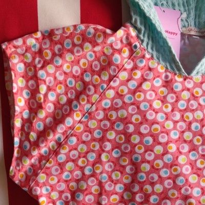 Roupa colorida com padrão de bolinhas e capuz azul texturizado