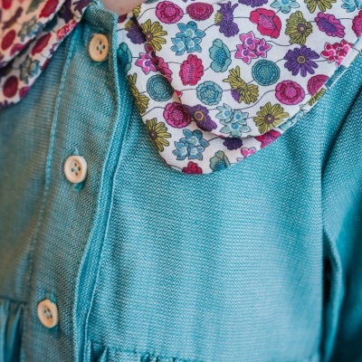 Vestido infantil azul com gola floral colorida e botões de madeira