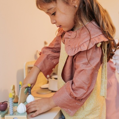 Menina a brincar com brinquedos de legumes de madeira