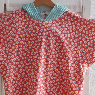 Capa de banho colorida com capuz verde água pendurada num cabide