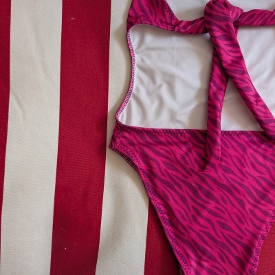 Fato de banho rosa riscas zebrado sobre tecido listrado vermelho e creme
