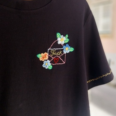T-shirt preta com bordado colorido de envelope e flores e texto Fuck