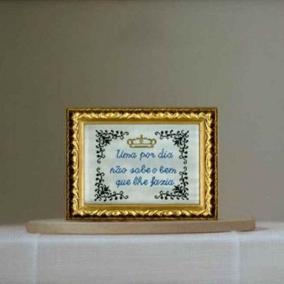 Quadro pequeno com moldura dourada e bordado com frase em tecido branco