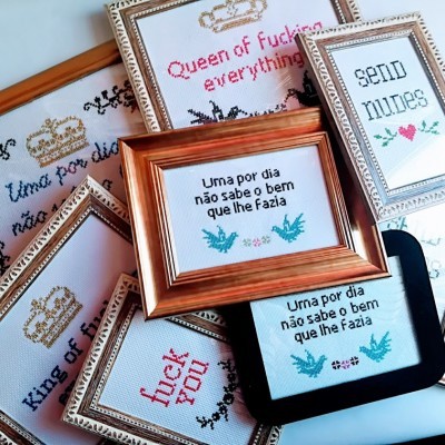 Quadros pequenos com mensagens bordadas em várias molduras sobre uma superfície branca