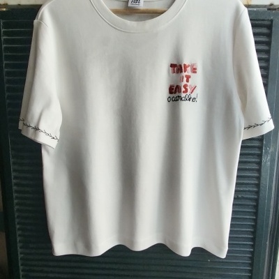 T-shirt branca com texto bordado vermelho e preto na frente