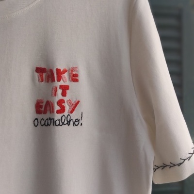 T-shirt branca com bordado colorido e costura preta na manga