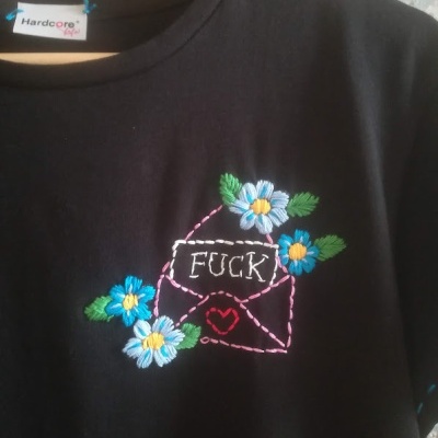 T-shirt preta com bordado colorido de flores e carta com palavra 'FUCK'