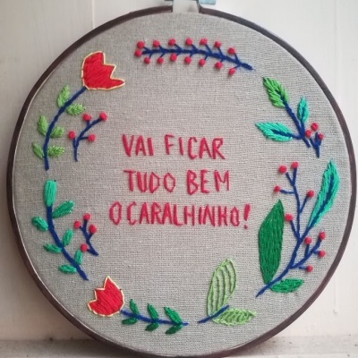 Bordado redondo com flores e texto em vermelho