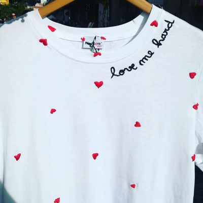 Camiseta branca com corações vermelhos e frase bordada no ombro