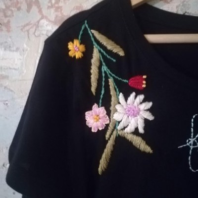 Camisola preta com bordados florais coloridos no ombro direito