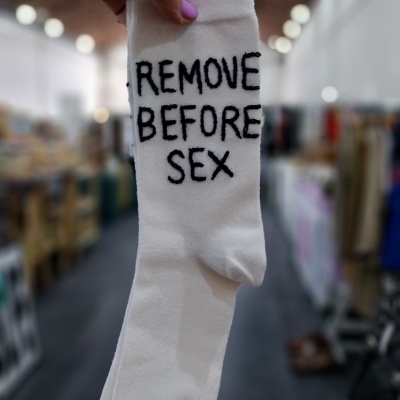 Meia branca com texto preto REMOVE BEFORE SEX numa loja