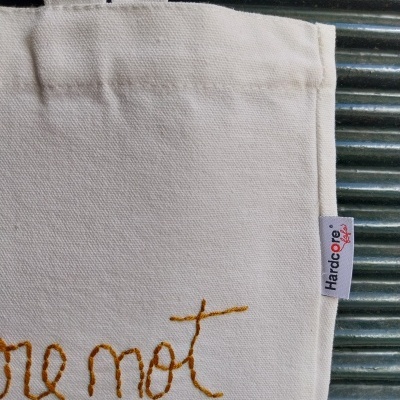 Saco de algodão cru com etiqueta lateral HARDCORE sobre superfície metálica ondulada