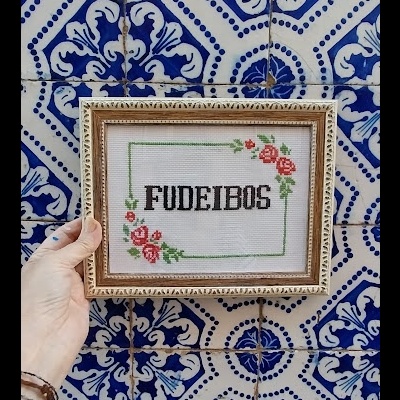 Moldura com bordado FUDEIBOS contra azulejos azuis e brancos