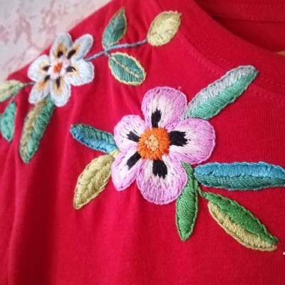 T-shirt vermelha com bordados florais coloridos no ombro