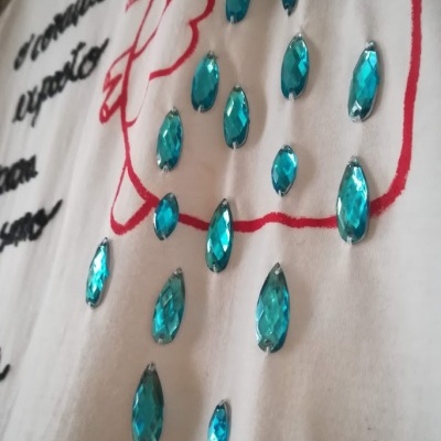 T-shirt branca com texto e pedras azuis aplicadas