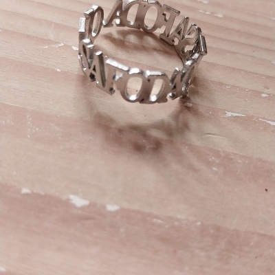 Anel prateado com letras maiúsculas em madeira clara