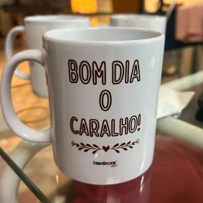 Caneca branca com texto em preto e detalhe floral vermelho