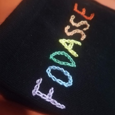 Tecido preto com bordado colorido a dizer FOODASSE