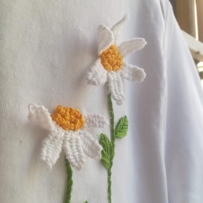 Camisola branca com bordado de duas flores brancas com centro amarelo e folhas verdes