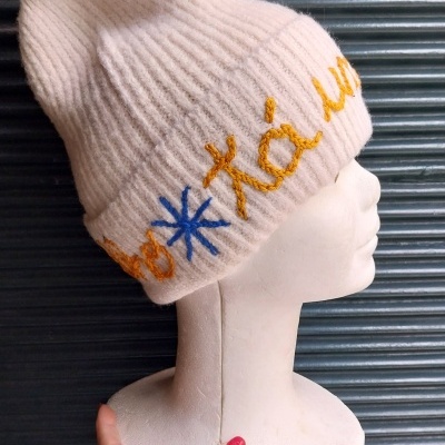 Gorro rosa claro com bordados coloridos num manequim branco