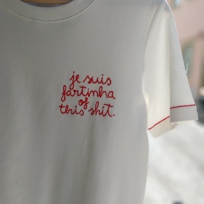 T-shirt branca com bordado vermelho e etiqueta visível