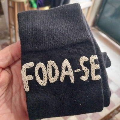 Meia preta com bordado branco a dizer 'FODA-SE'