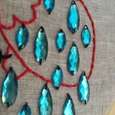 Pedras azuis facetadas em tecido bordado vermelho e preto