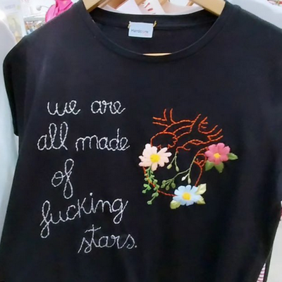 T-shirt preta com bordado de texto e coração com flores