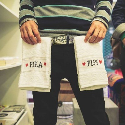 Pessoa segurando toalhas brancas com textos bordados numa loja