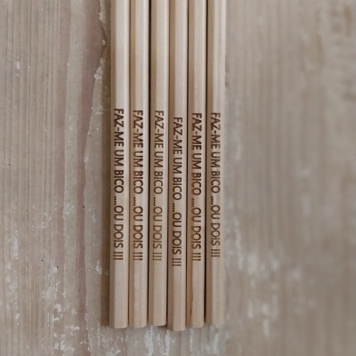 Seis lápis de madeira com frase gravada alinhados sobre superfície de madeira