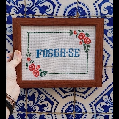 Moldura com bordado FOSGA-SE contra parede de azulejos azuis e brancos