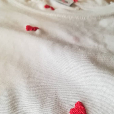 Camisola branca com corações bordados vermelhos e etiqueta na gola