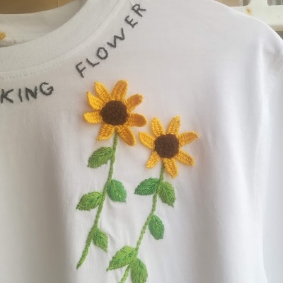Camisola branca com flores amarelas bordadas e texto 'KING FLOWER'