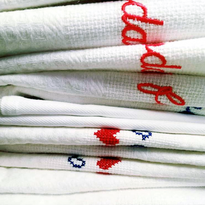 Panos de prato brancos com bordados vermelhos e azuis empilhados