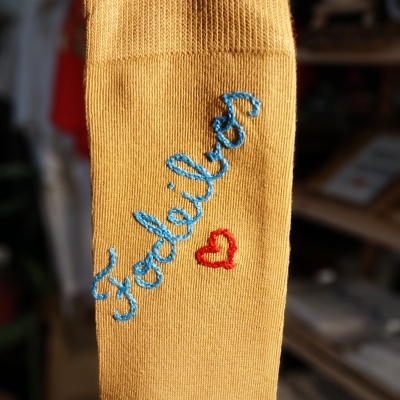 Meia amarela com bordado azul 'Foodella' e coração vermelho